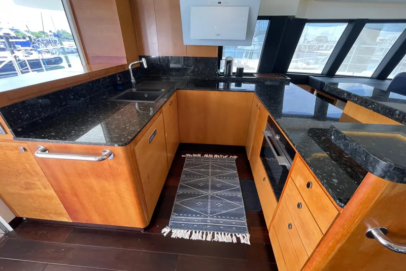 Slide: The Image of Luxurious 2018 Serenity 64 yacht kitchen with sleek black countertops and wooden cabinetry. - 44