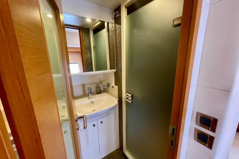 Slide: The Image of Compact bathroom with modern sink, mirror, and frosted glass shower door in Serenity 64 yacht. - 65