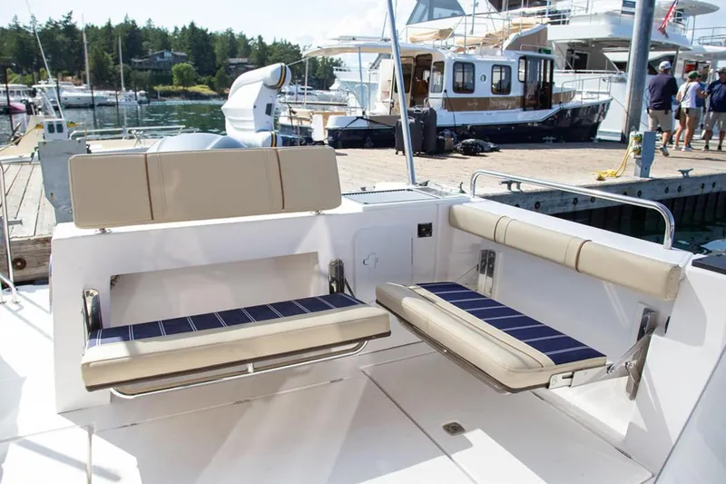 Slide: The Image of Manufacturer Provided Image: 2025 Ranger Tugs R-25 boat seating area at marina, featuring beige and blue cushions. - 5