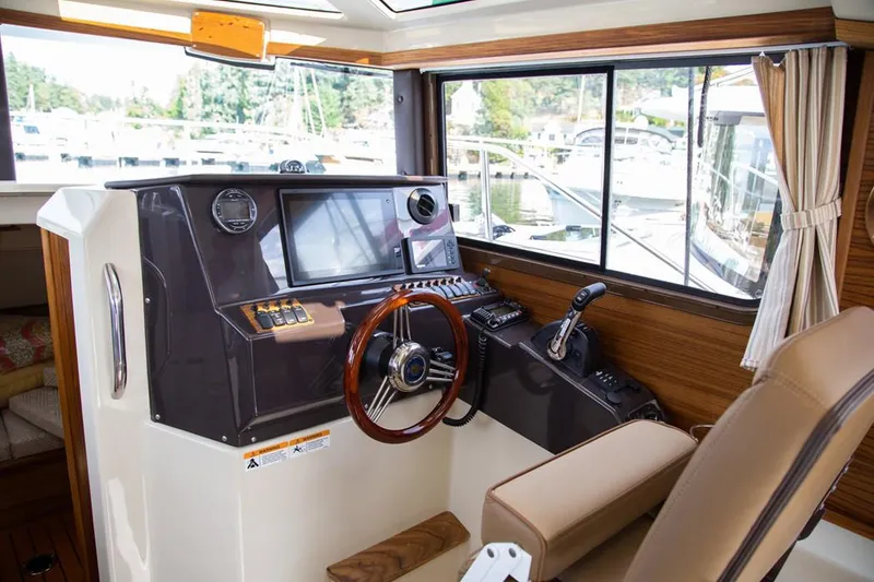 Slide: The Image of Manufacturer Provided Image: 2025 Ranger Tugs R-25 helm with modern controls and wood accents. - 6