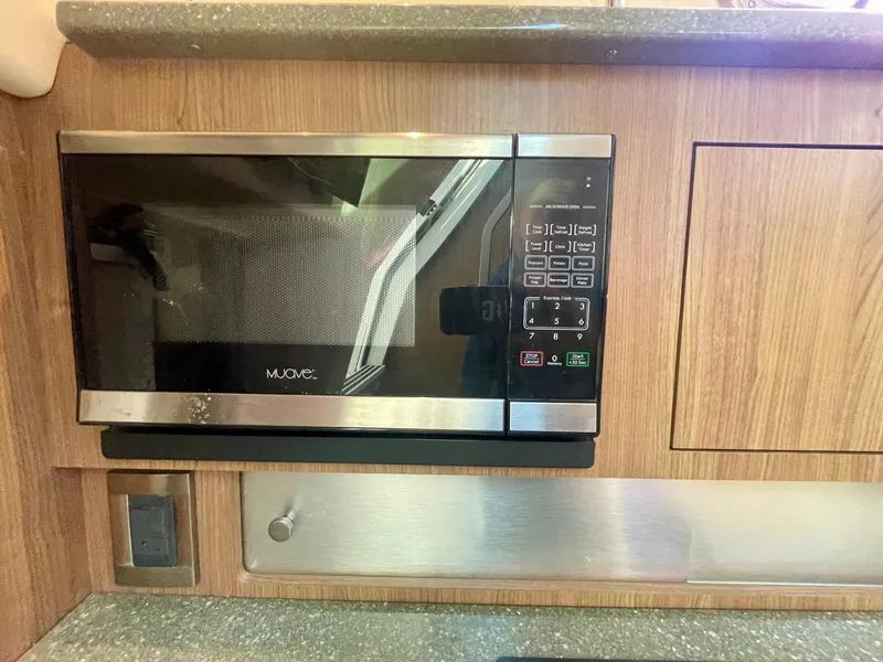 Slide: The Image of Microwave in 2018 Boston Whaler 315 Conquest boat kitchen, wood paneling, and countertop. - 35
