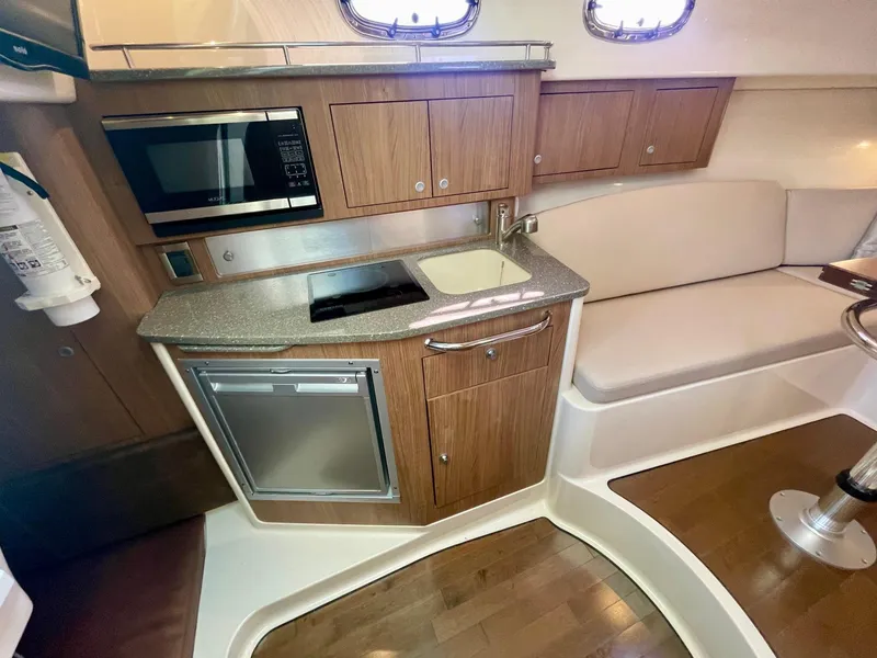Slide: The Image of 2018 Boston Whaler 315 Conquest interior with kitchenette, featuring microwave, sink, and seating area. - 37