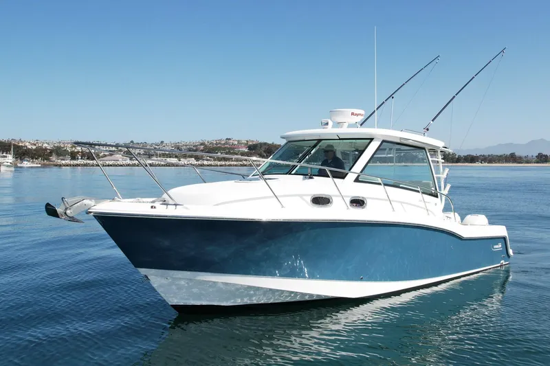Slide: The Image of 2018 Boston Whaler 315 Conquest boat on calm water, featuring a sleek blue and white design. - 6