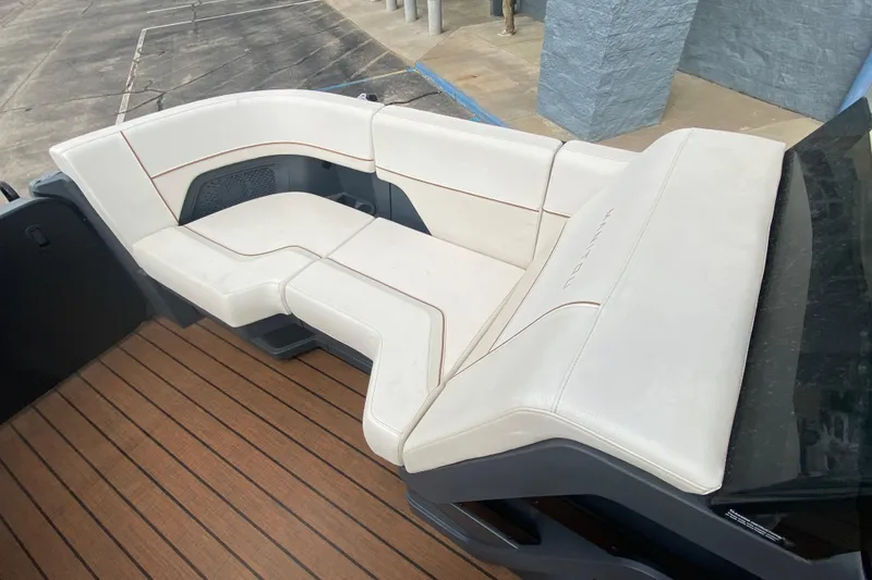 Slide: The Image of 2024 Manitou 22 MAX Explore Navigator Stealth boat seating with white upholstery and wood flooring. - 10