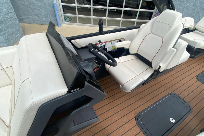 Slide: The Image of 2024 Manitou 22 MAX Explore Navigator Stealth boat interior with sleek helm and seating. - 11
