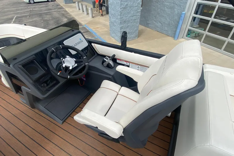 Slide: The Image of 2024 Manitou 22 MAX Explore Navigator Stealth boat interior with steering wheel and seating. - 12
