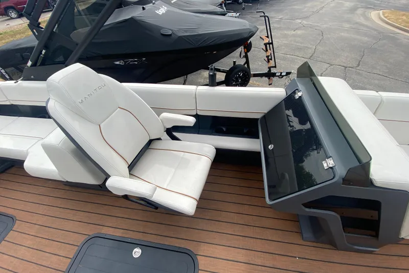 Slide: The Image of 2024 Manitou 22 MAX Explore Navigator Stealth boat interior with white seating and sleek console. - 17