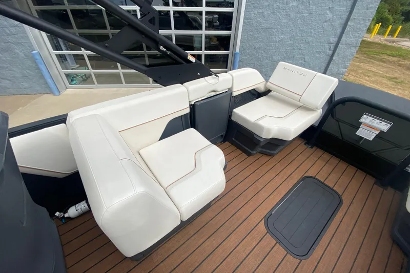 Slide: The Image of 2024 Manitou 22 MAX Explore Navigator Stealth boat interior with white seating and wood flooring. - 19