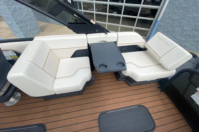 Slide: The Image of 2024 Manitou 22 MAX Explore Navigator Stealth boat seating with table on wooden deck. - 21
