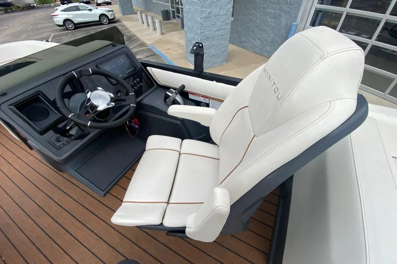 Slide: The Image of 2024 Manitou 22 MAX Explore Navigator Stealth helm with white seating and modern controls. - 24