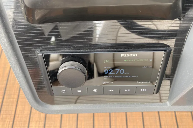 Slide: The Image of 2024 Manitou 22 MAX Explore Navigator Stealth radio display showing FM station 92.7 MHz. - 25