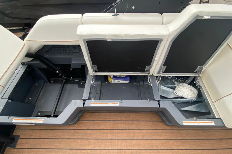 Slide: The Image of 2024 Manitou 22 MAX Explore Navigator Stealth storage compartments with open seats and visible equipment. - 28