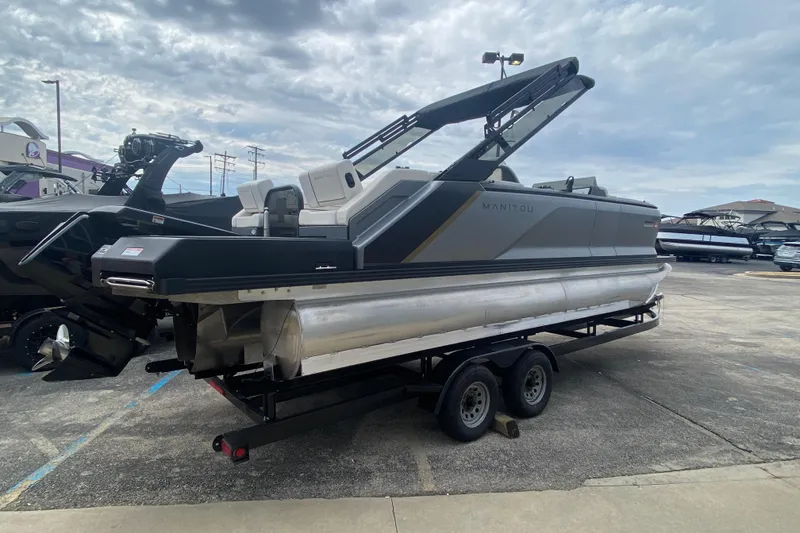 Slide: The Image of 2024 Manitou 22 MAX Explore Navigator Stealth pontoon boat on trailer, parked outdoors. - 6
