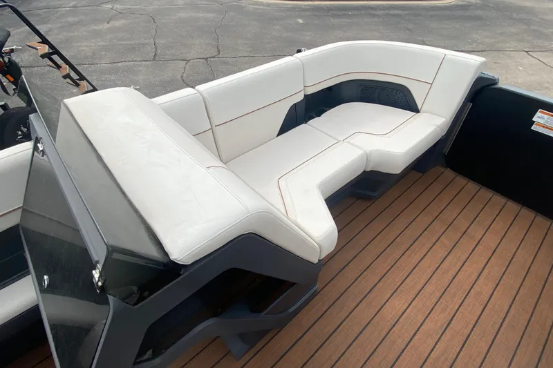 Slide: The Image of 2024 Manitou 22 MAX Explore Navigator Stealth boat interior with white seating and wood flooring. - 9