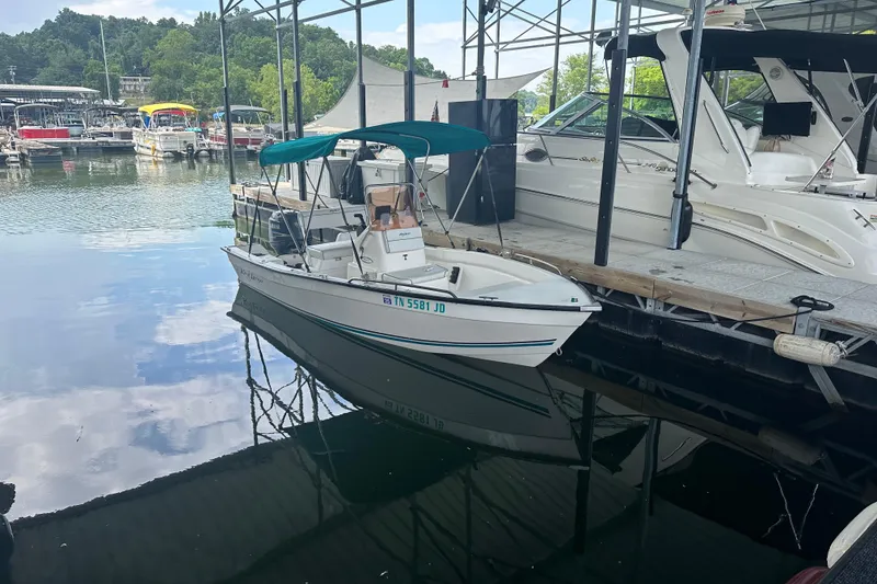 Slide: The Image of 2006 Key Largo 160 Center Console boat docked at a marina with calm water reflections. - 5