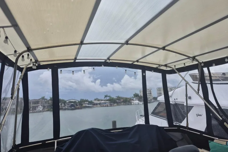 Slide: The Image of 1986 Sea Ray 410 Aft Cabin boat interior with marina view, covered deck, and string lights. - 10