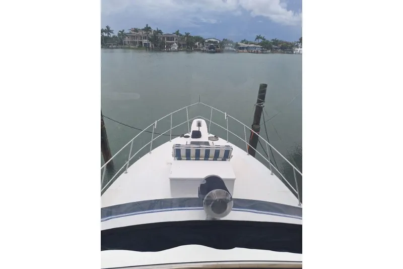 Slide: The Image of 1986 Sea Ray 410 Aft Cabin yacht docked in a serene waterfront setting. - 15