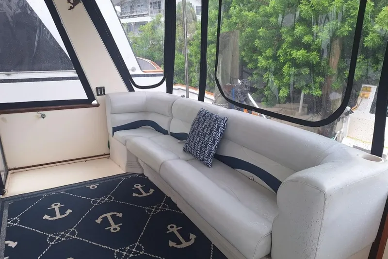 Slide: The Image of 1986 Sea Ray 410 Aft Cabin interior with white sofa, nautical-themed rug, and decorative pillow. - 19