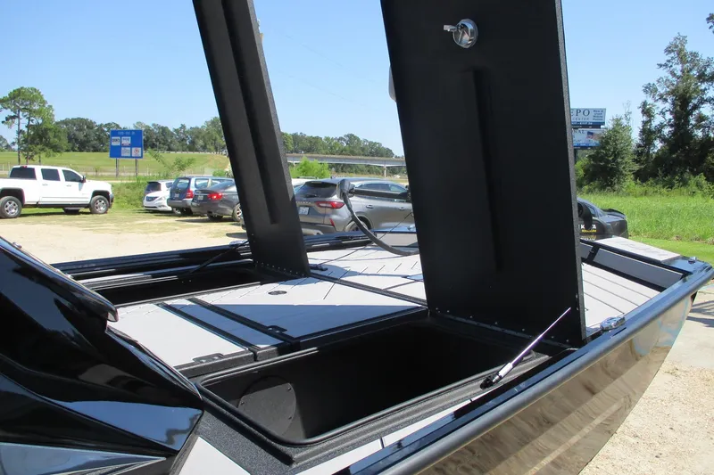 Slide: The Image of 2026 Avid 20 Vertex boat with open storage compartments in a parking area. - 7