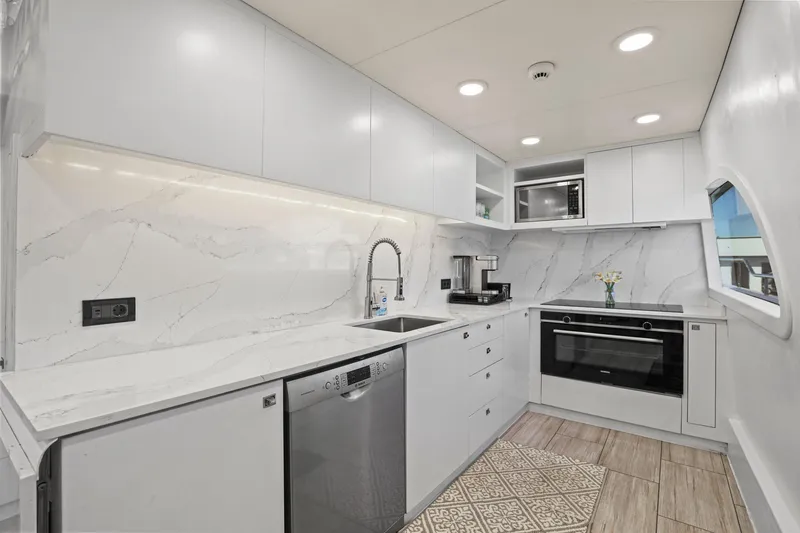Slide: The Image of Modern yacht kitchen with sleek white cabinetry, marble backsplash, and stainless steel appliances on Mengi Yay 115 MY. - 48