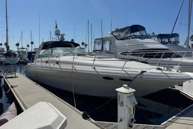 Slide: The Image of 2000 Sea Ray 410 Express Cruiser docked at marina under clear blue sky. - 0