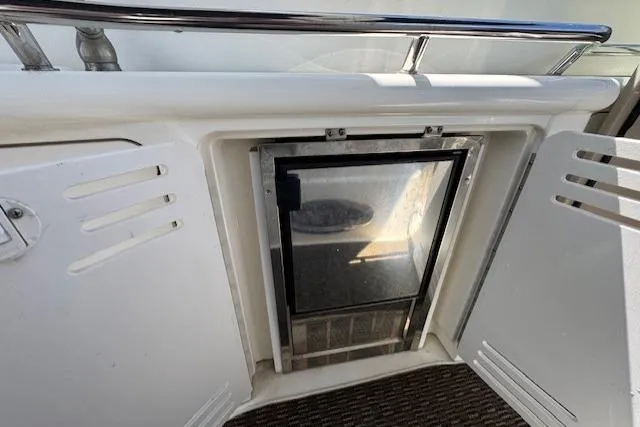 Slide: The Image of 2000 Sea Ray 410 Express Cruiser interior with built-in mini fridge and storage. - 20