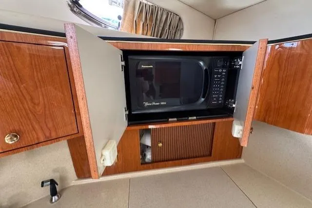 Slide: The Image of 2000 Sea Ray 410 Express Cruiser kitchen with microwave in wooden cabinetry. - 6