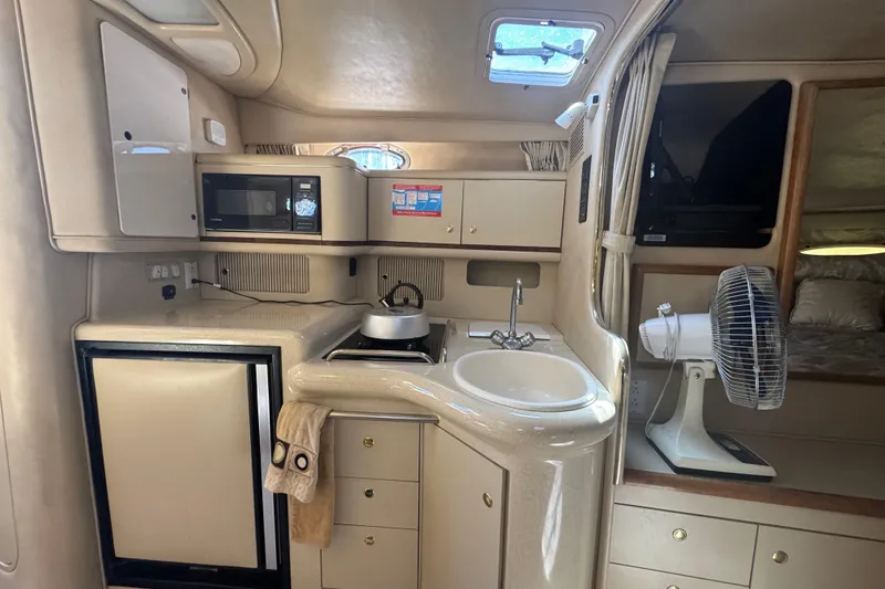 Slide: The Image of 1998 Sea Ray 330 Sundancer interior with kitchenette, sink, microwave, and fan. - 19