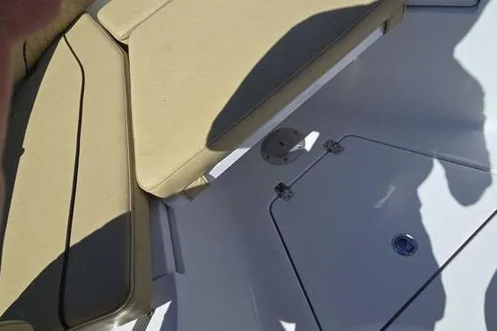 Slide: The Image of 2023 Sportsman Open 242 Center Console boat interior with beige seating and storage compartment. - 12