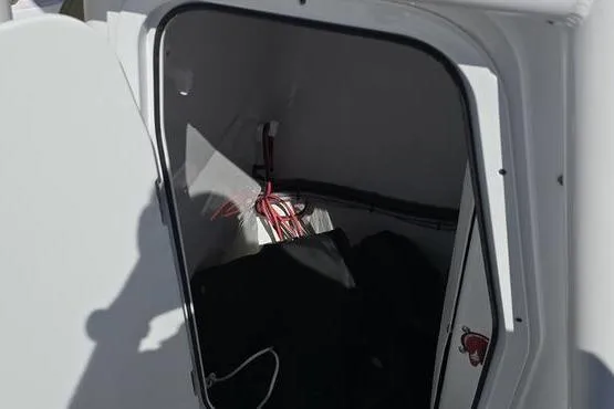 Slide: The Image of 2023 Sportsman Open 242 Center Console storage compartment with wiring and equipment inside. - 4