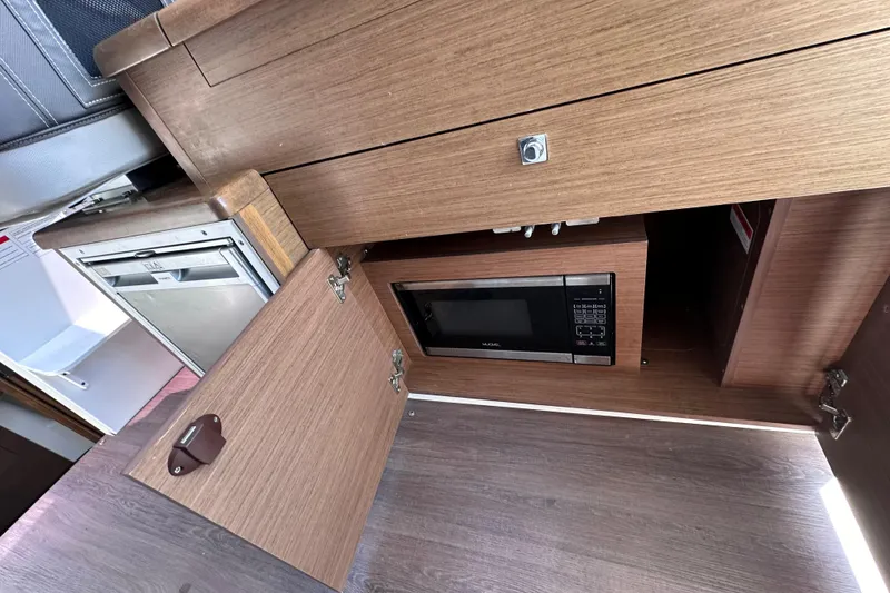 Slide: The Image of 2019 Jeanneau 895 interior kitchen with microwave and wooden cabinetry. - 14