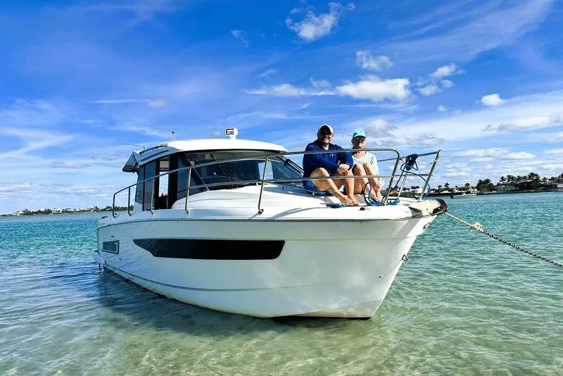 Slide: The Image of 2019 Jeanneau 895NC boat with two people relaxing on deck in clear blue water. - 4