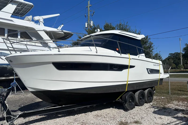 Slide: The Image of 2019 Jeanneau 895 boat on trailer, parked outdoors under clear blue sky. - 5