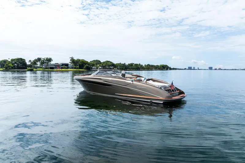 Slide: The Image of 2014 Riva Rivarama luxury yacht on calm water, with scenic shoreline background. - 5