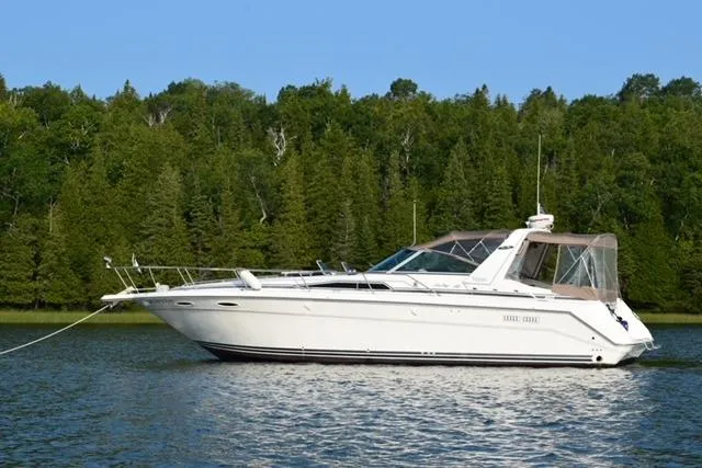 The Image of 1992 Sea Ray 370 Express Cruiser on tranquil lake with forest backdrop. - 1