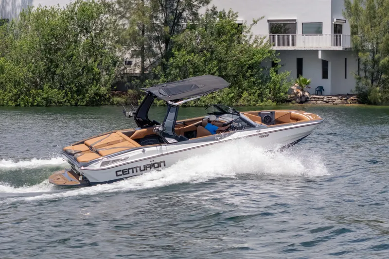 Slide: The Image of 2025 Centurion Nv233 boat cruising on a lake near a modern house. - 32