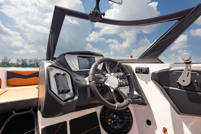 Slide: The Image of 2025 Supreme S220 boat dashboard with steering wheel and control panel under a clear sky. - 13