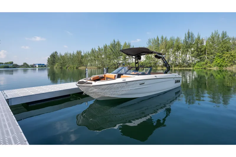 Slide: The Image of 2025 Supreme S220 boat docked on a serene lake with lush greenery. - 16