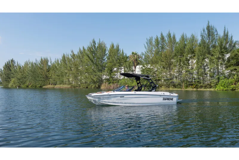 Slide: The Image of 2025 Supreme S220 boat cruising on a serene lake with lush green trees. - 19