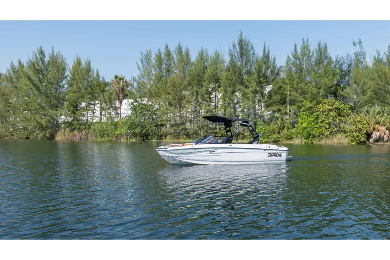Slide: The Image of 2025 Supreme S220 boat cruising on a serene lake with lush greenery. - 20