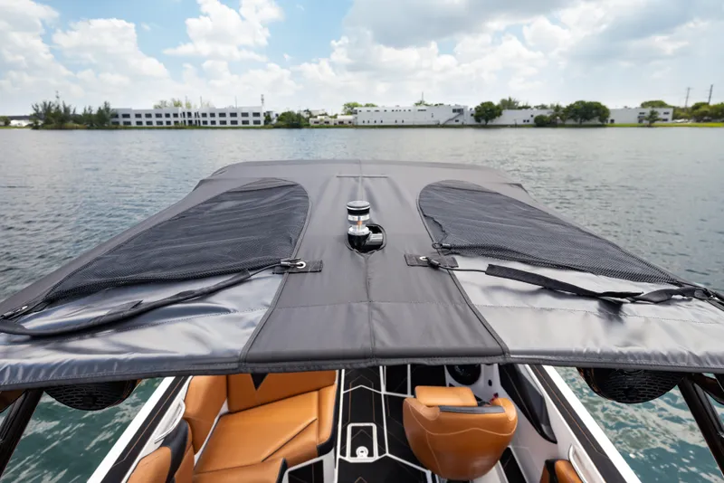 Slide: The Image of 2025 Supreme S220 boat with sleek black canopy and tan interior on a calm lake. - 21