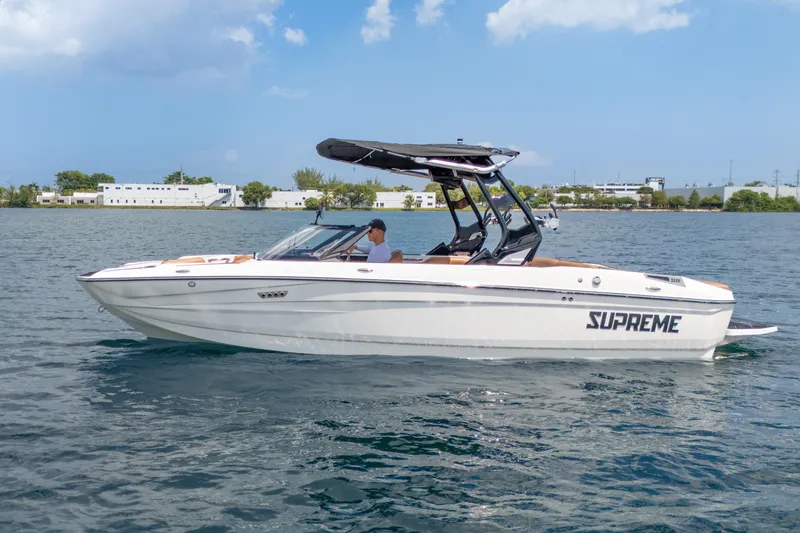 Slide: The Image of 2025 Supreme S220 boat cruising on a calm lake under a clear blue sky. - 25