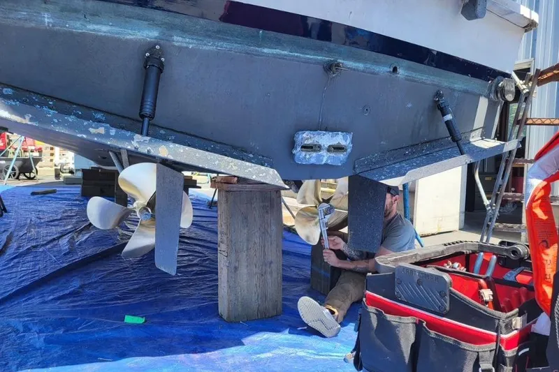 Slide: The Image of 1973 Uniflite Sport Fisher boat maintenance with visible propellers and tools. - 140