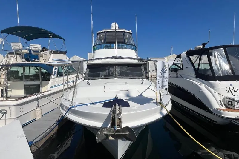 Slide: The Image of 1973 Uniflite Sport Fisher boat docked between two other vessels under clear blue sky. - 3