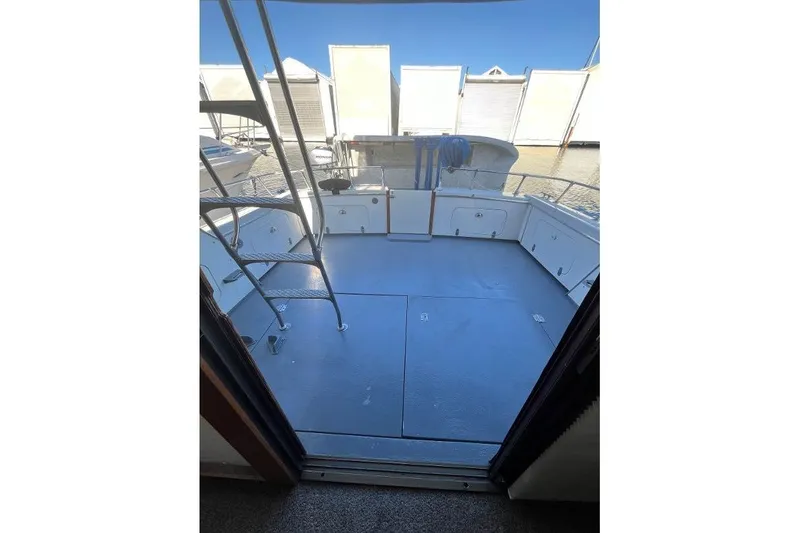 Slide: The Image of 1973 Uniflite Sport Fisher boat deck with storage compartments and ladder, docked by the water. - 31