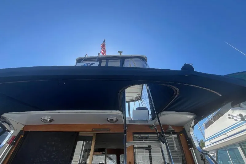 Slide: The Image of 1973 Uniflite Sport Fisher boat with canopy and American flag under clear blue sky. - 36