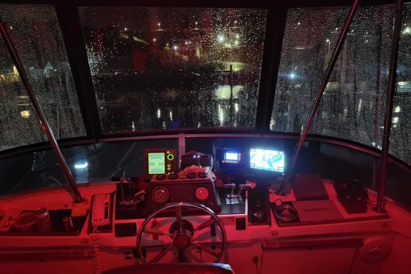 Slide: The Image of 1973 Uniflite Sport Fisher boat cockpit at night, illuminated with red lighting and rain on windows. - 41