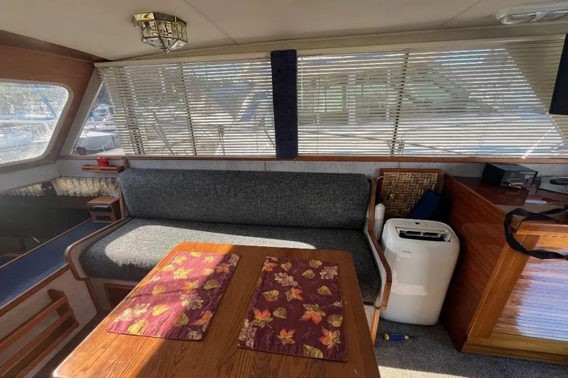 Slide: The Image of 1973 Uniflite Sport Fisher interior with cozy seating, wooden table, and floral placemats. - 58