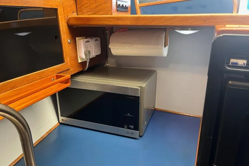Slide: The Image of 1973 Uniflite Sport Fisher kitchen with microwave, paper towel holder, and wooden cabinetry. - 80