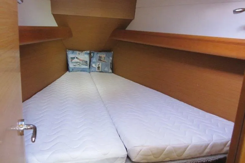 Slide: The Image of Cozy cabin interior of 2013 Jeanneau 379 sailboat with twin mattresses and nautical-themed pillows. - 14
